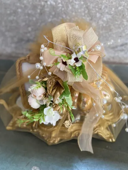 A close-up of our classic gold-wrapped gift, showcasing the intricate bow made of tulle, pearls, and soft florals. This image emphasizes the delicate, handcrafted details that define our brand.