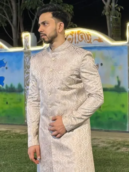 A client looking sharp in a beige brocade sherwani, a perfect outfit for a groomsman or a wedding guest.