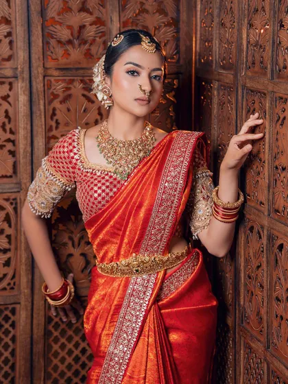 The beauty is in the details. This image highlights the delicate embroidery on the blouse and the rich border of the red silk saree, perfect for a traditional wedding.