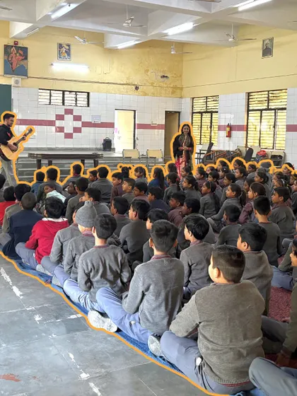 A large group of students sits in rapt attention during a music session in their school hall. We use these opportunities to spread messages of hope and unity through songs like "Umeed Hai."