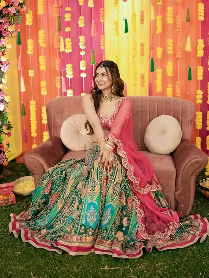The bride looking regal on her Sangeet stage, surrounded by vibrant floral decorations.