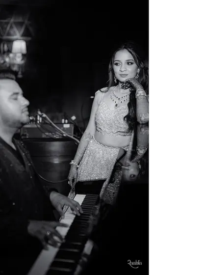 A candid moment during the Sangeet night. The bride's shimmering lehenga and the groom at the piano create a picture of modern romance.