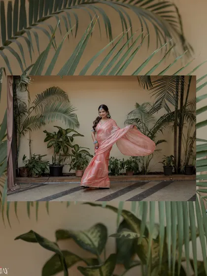 A beautiful shot of the bride twirling in her pink saree against a backdrop of lush palm trees.