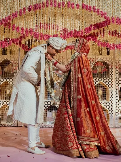 A tender moment shared between the couple against an opulent floral backdrop. We designed this intricate wall of white and pink floral strings to create a rich, textured setting for their special day.