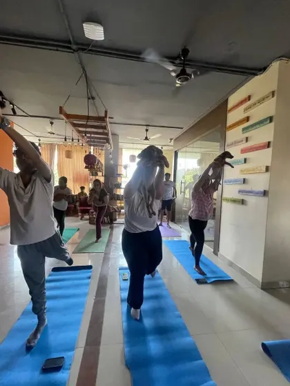 Participants in tree pose, with one yogi playfully lifting a puppy. These classes are filled with laughter and love.