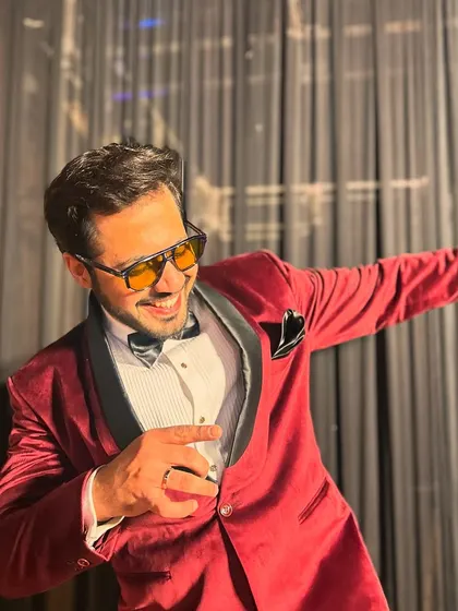 A playful pose in a striking red velvet tuxedo, perfect for making a statement at a Sangeet or reception.