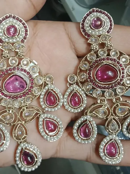 A pair of large, round statement earrings with pink stones and Polki work. The design is bold and beautiful, perfect for weddings and festive occasions.