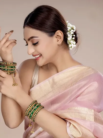 A candid-style shot of the model admiring the green bangles, creating a relatable and aspirational moment for a lifestyle jewellery campaign.