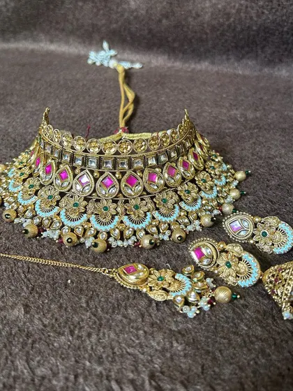 A bridal choker set in a Jadau Kundan style with pink stones and mint green accents. This rental includes the choker, earrings, and a matching maang tikka.
