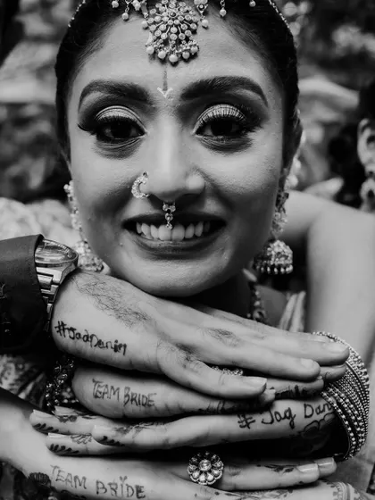 A black and white portrait of a bride, her hands adorned with Mehendi and temporary tattoos for her bridal party. This unique detail adds a fun and personal touch to her wedding look.