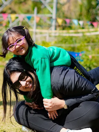 A teacher and student sharing a happy piggyback ride on the lawn during a school outing.
