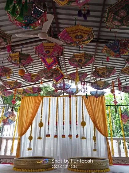 For a Haldi ceremony, you need energy and color. This setup features a ceiling full of vibrant Rajasthani umbrellas and a classic marigold backdrop, creating a festive atmosphere.