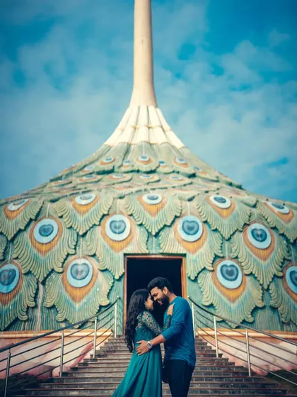 A romantic embrace in front of a stunning peacock-themed building, blending unique architecture with a tender moment.