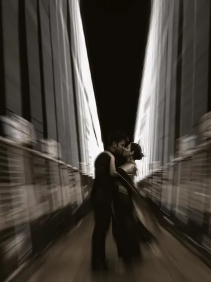 A filmic, motion-blur shot of a couple kissing on a bridge at night, creating a dramatic and romantic cinematic feel.