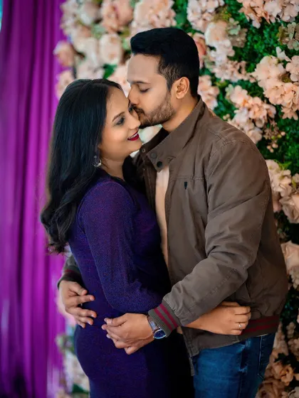 An intimate and happy moment between a couple during their pre-wedding photoshoot. The floral background adds a touch of romance and softness to the portrait.