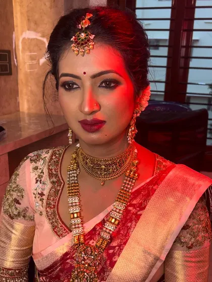 This bride is ready for her ceremony, showcasing a beautiful look with a bright pink lip that pops against her elegant saree. The makeup is designed to be long-lasting and picture-perfect.