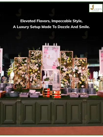 An elegant and modern buffet station featuring a dark green paneled counter, framed floral backdrops, and neatly stacked luxury plates, ready for guests.