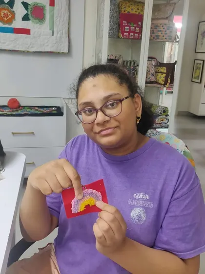 A participant showing the pastel rainbow she created on a piece of red fabric.