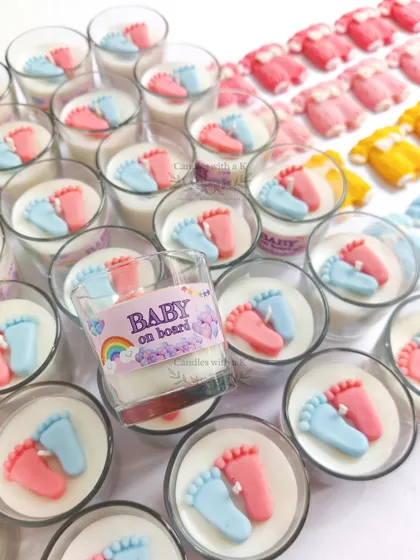 A close-up of the 'Baby on Board' votive candle, featuring tiny pink and blue feet. This is a popular and heartwarming choice for baby shower return gifts.
