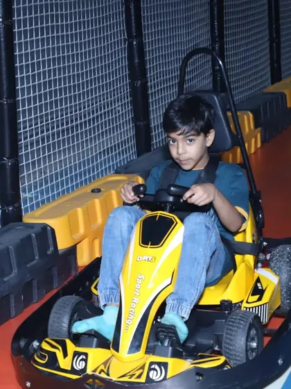 A cool and confident driver in a yellow go-kart, ready to take on the challenge of the track.