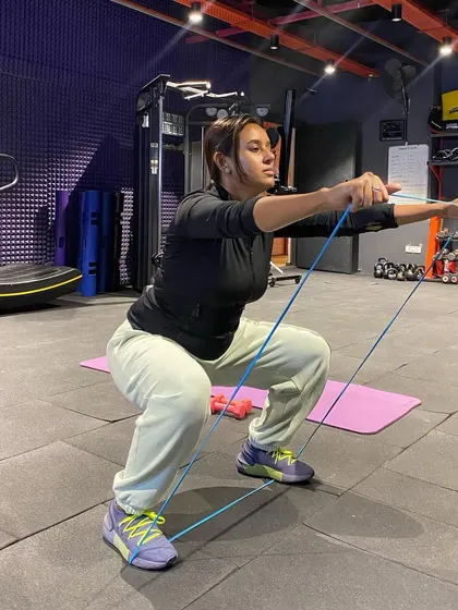 Resistance bands are a versatile tool for adding challenge to any exercise. Here, we're using one to increase the intensity of a squat, focusing on glute and quad activation.