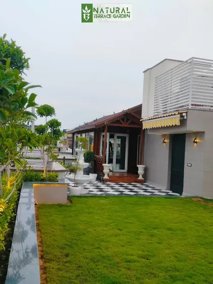 A completed terrace project in New Friends Colony, New Delhi. This expansive garden features a natural lawn, a wooden cottage, and a checkered patio.