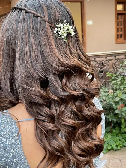 A pretty and simple open hairstyle for a bridesmaid or guest. The soft curls are given a touch of elegance with a simple braid and fresh flowers.