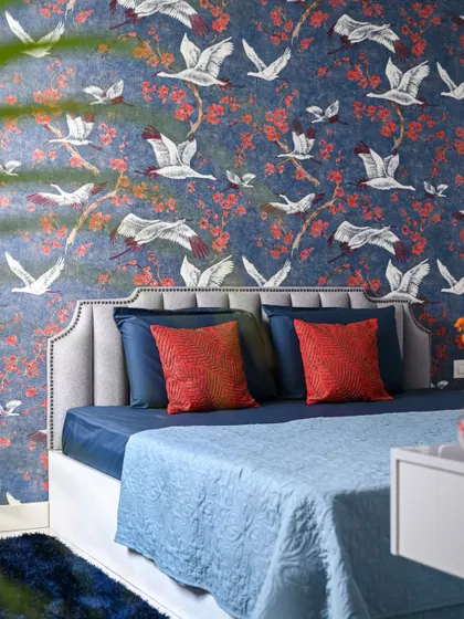 This master bedroom features a stunning accent wall with a crane and cherry blossom wallpaper. The deep blue and red tones create a dramatic and luxurious feel.