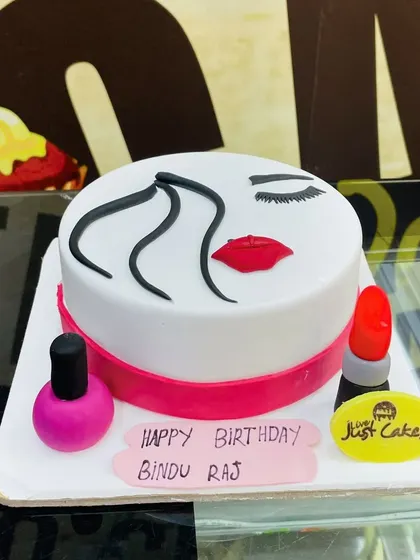 A chic 1.5kg makeup theme cake with a minimalist face design and fondant lipstick and nail polish.