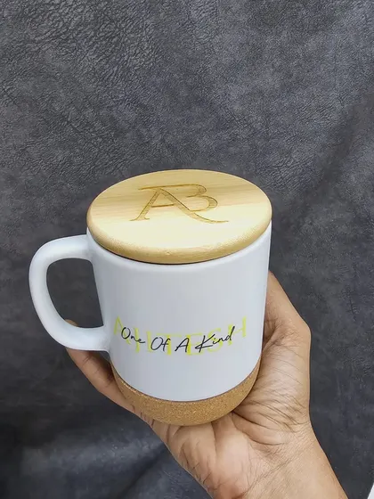 This modern ceramic mug features a natural cork base and a wooden lid that can be engraved with initials. The mug itself can also be customized with a name or a unique design.