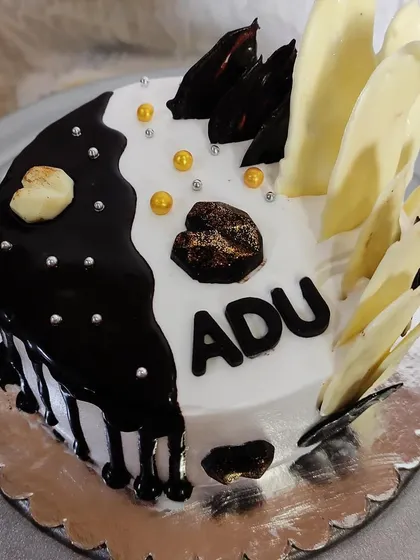 This half-and-half cake offers the best of both worlds. One side has a dark chocolate drip with modern shards, while the other is clean white buttercream with white chocolate accents.
