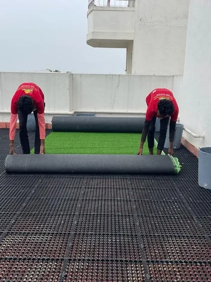 Our team carefully rolling out high-quality artificial turf over the drainage cell layer, ensuring a perfectly smooth and even green surface.