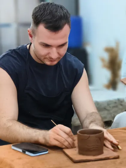 A student carefully carves a design into his hand-built pot. Our studio is a melting pot of cultures and creativity.