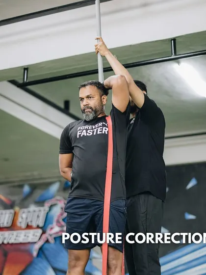 Posture correction is a key element of our training. Here, a coach uses a dowel and resistance band to provide tactile feedback, helping a client improve their alignment and movement mechanics.