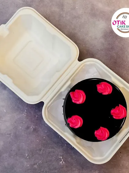 A rich chocolate bento cake decorated with vibrant pink buttercream roses. The contrast between the dark chocolate and bright pink makes it visually striking.