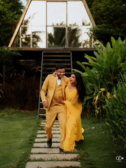 A happy, walking shot of the couple in yellow, their laughter echoing the joy of their pre-wedding shoot at the A-frame house.