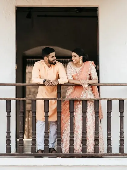Nikhil and Varsha sharing a quiet moment on a balcony in a Goan villa, dressed in elegant traditional wear.