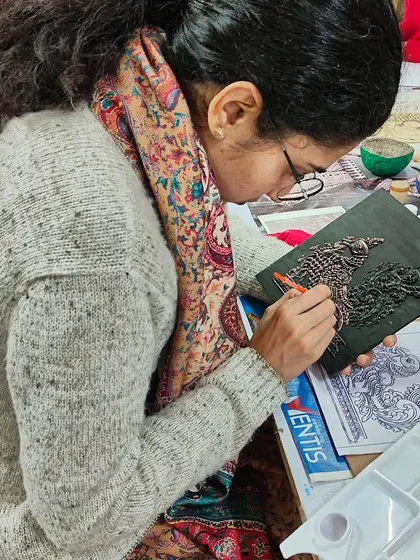 A student meticulously working on a traditional relief panel. This art form involves creating a raised design on a flat surface, adding depth and texture.