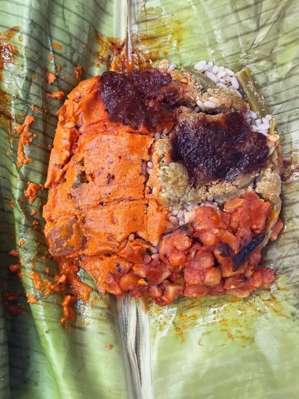 A freshly unwrapped Pothichoru, revealing the beautiful medley of flavors inside. You can see the red rice, colorful curries, and rich chutney all steamed together. It's a culinary gem that's both traditional and trendy.