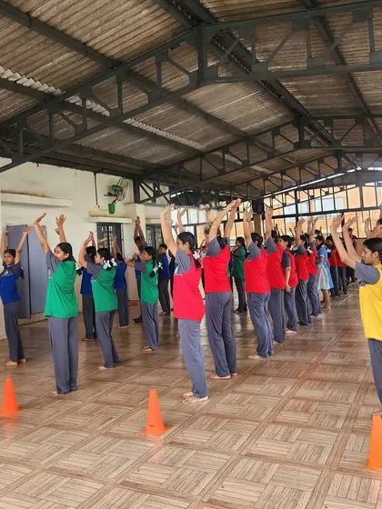 Students raise their arms in a coordinated yoga pose. Our sessions focus on discipline and unity, as players learn to move together as one.