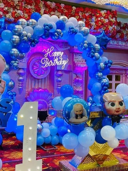 A close-up of the 'Boss Baby' birthday theme, showing the character cutouts, balloon columns, and a 'Happy Birthday' neon sign against a grand backdrop.