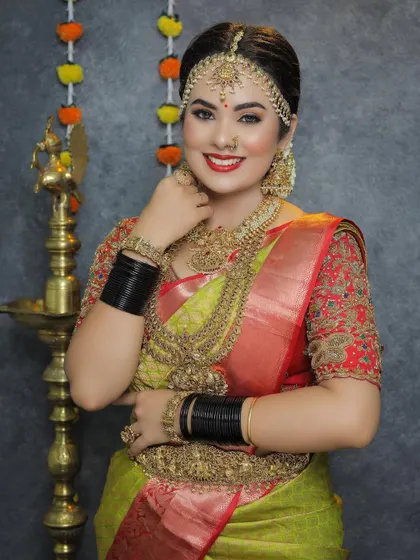 This bride is all smiles, looking radiant in a full temple jewellery set. The matha patti, layered necklaces, and black bangles create a striking contrast.