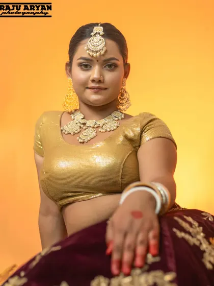 A seated portrait showcasing the full styling of our vintage theme, from the golden blouse to the intricate jewelry. The warm, solid background keeps the focus entirely on the model.