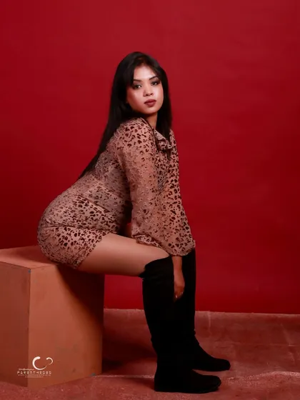 A confident seated pose that showcases the full outfit. The composition is balanced, and her expression is strong and steady.