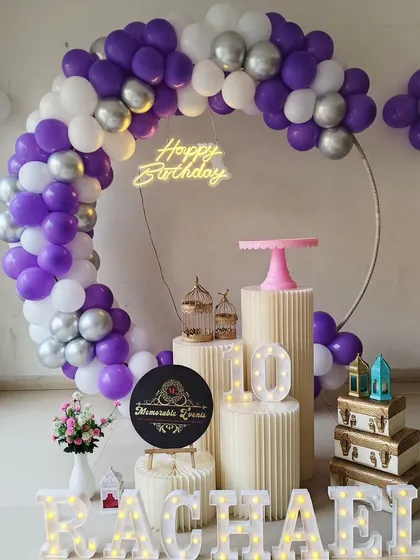 A 10th birthday party setup with a purple and white balloon ring, marquee letters, and number.