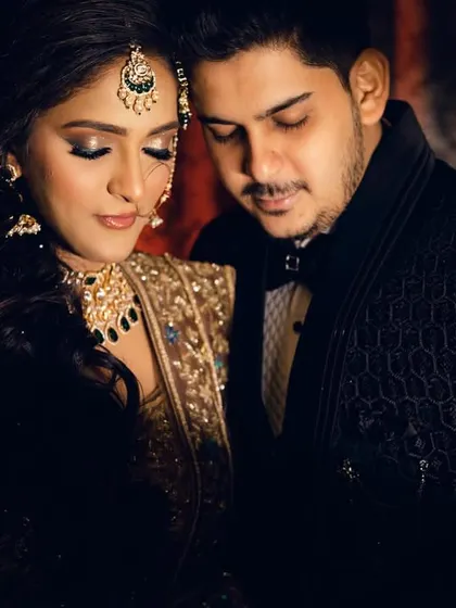 A quiet, intimate moment between the couple, their faces close together. The warm, dramatic lighting highlights their features and the intricate details of their wedding attire, creating a deeply romantic mood.