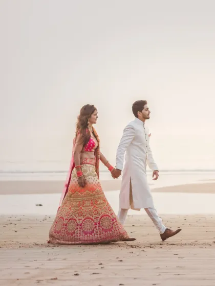 A side-profile shot of the couple walking on the beach at dusk. The soft light and their connected hands create a simple yet powerful image of togetherness.
