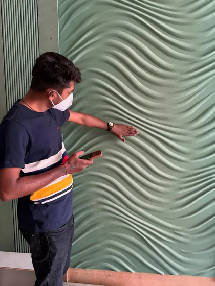 Inspecting the texture and finish of the 3D wall panel up close. Quality control is a continuous process.