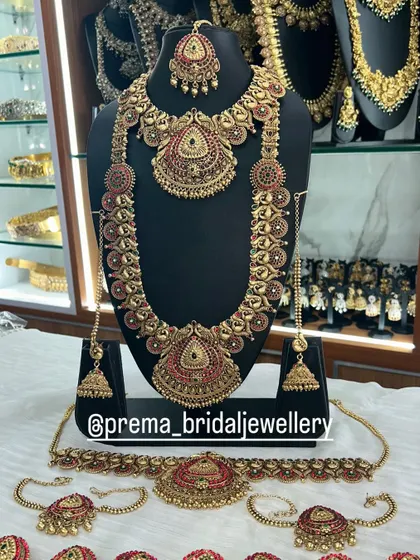 A full bridal set with red Kemp stones, including choker, haaram, vaddanam, and armlets (vanki).