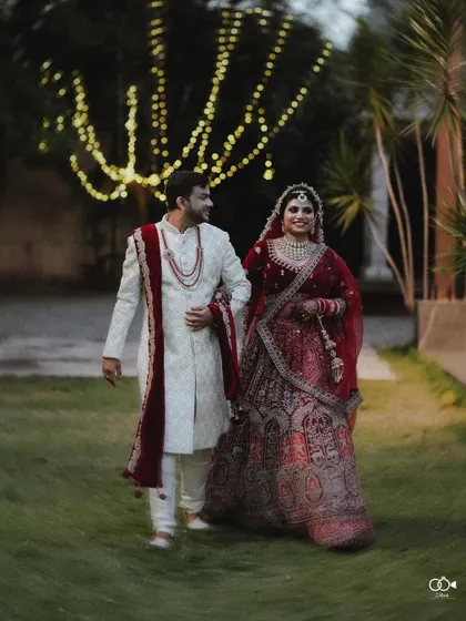 A beautiful portrait of the couple walking through a garden at night, illuminated by fairy lights.